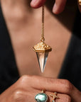 Hand holding Ananda Soul's Oracle of Light gold pendulum with crystal quartz